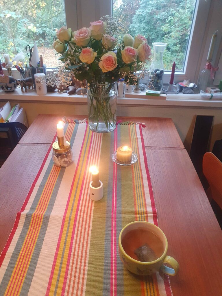 Eine hyggelige Tischbedeckung mit einem Set, Blumen und Kerzen